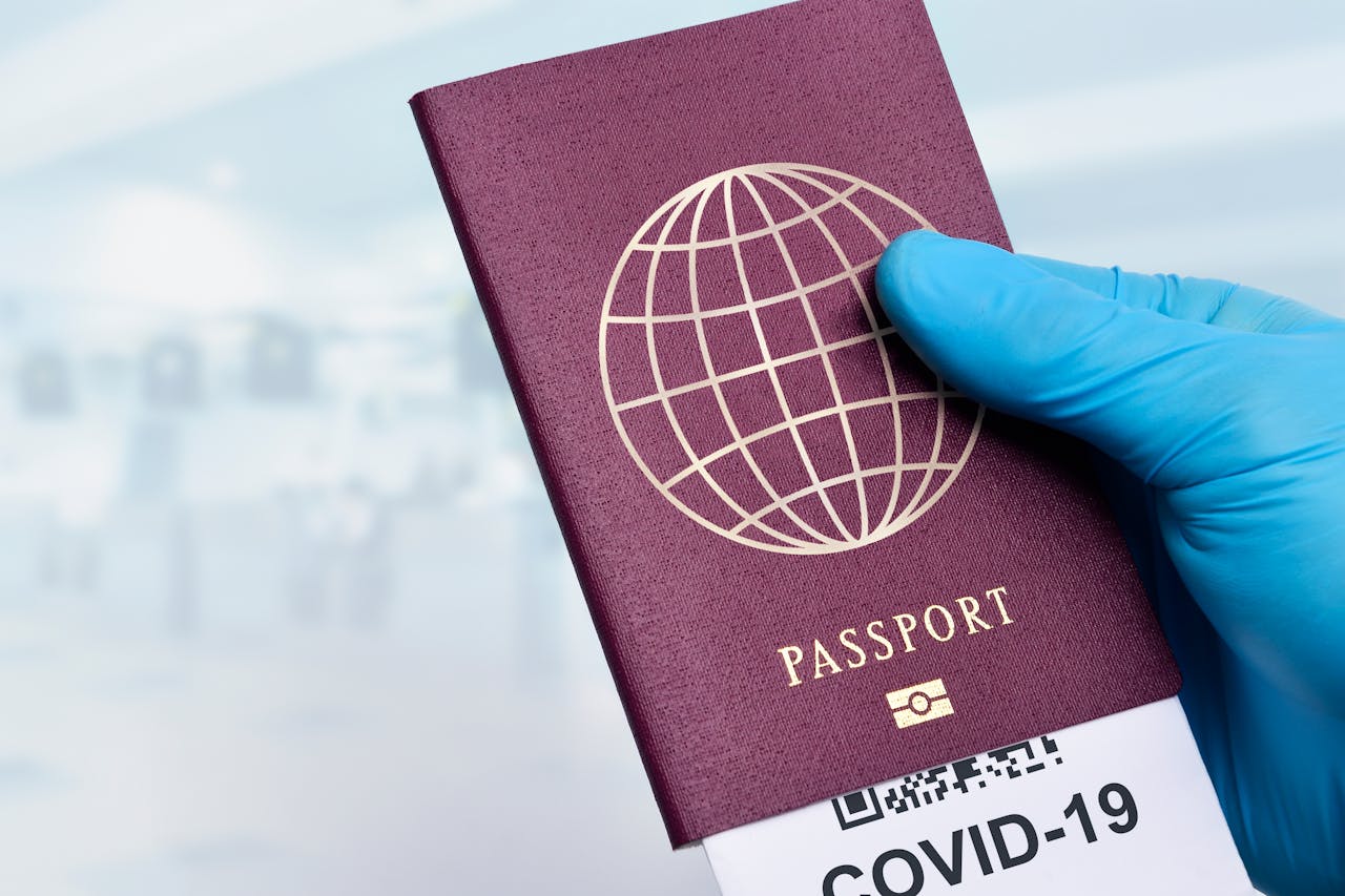 Services Close-up of a gloved hand holding a passport with a COVID-19 ticket, symbolizing pandemic travel.