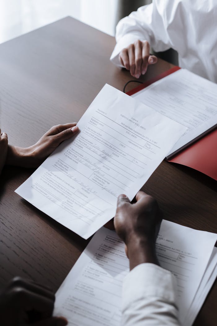 Services Adults reviewing legal documents on a wooden desk indoors, highlighting professional collaboration.